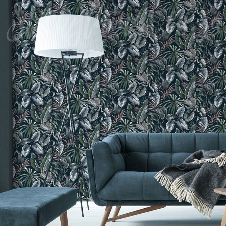 Dark Exotique Leaves Wallpaper on a living room wall behind a sofa and a lamp